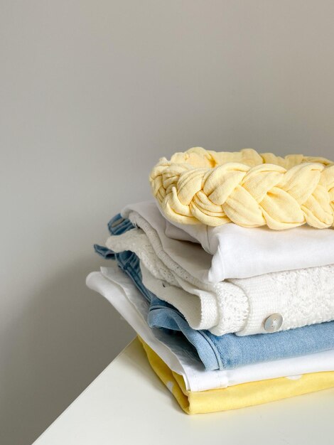 Pila di cotone di vestiti piegati colorati su tavolo bianco all'interno spazio vuoto sfondo Abito estivo primo piano