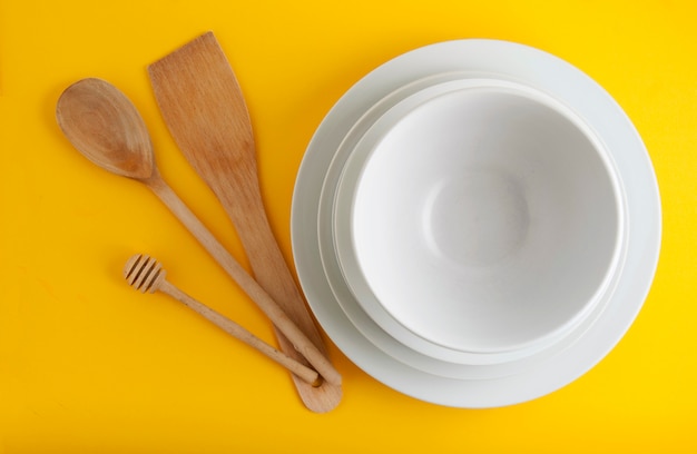 Pila di diversi piatti bianchi, ciotole. Isoalted su sfondo giallo.