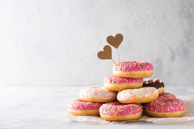 Pila di donat rosa e bianchi su bianco