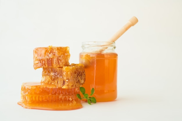 Pila di favi con erba e vaso di miele