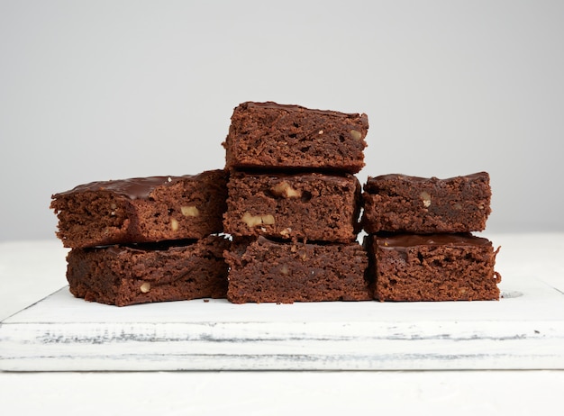 Pila di fette al forno quadrate di torta al cioccolato brownie con noci