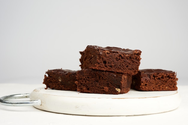 Pila di fette al forno quadrate di torta al cioccolato brownie con noci