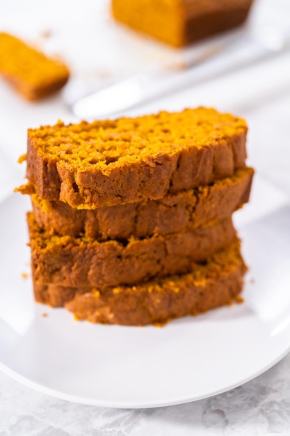 Pila di fette di pane di zucca fatte in casa su un piatto bianco