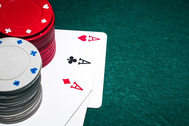 Pila di fiches del casinò bianco e rosso sopra i tre assi sul tavolo da poker