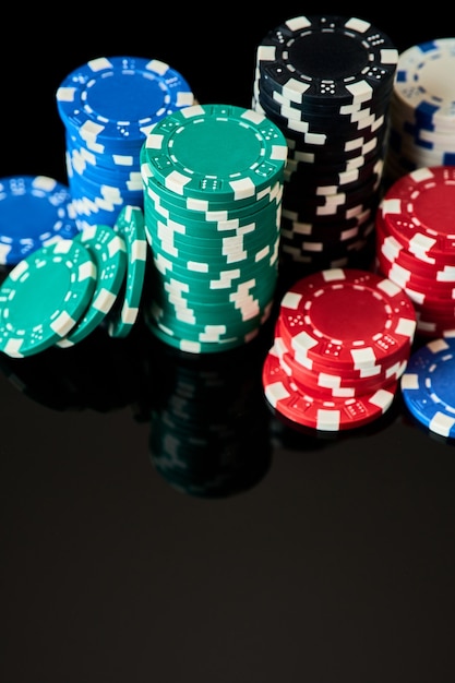 Pila di fiches del casinò isolate su sfondo nero riflettente