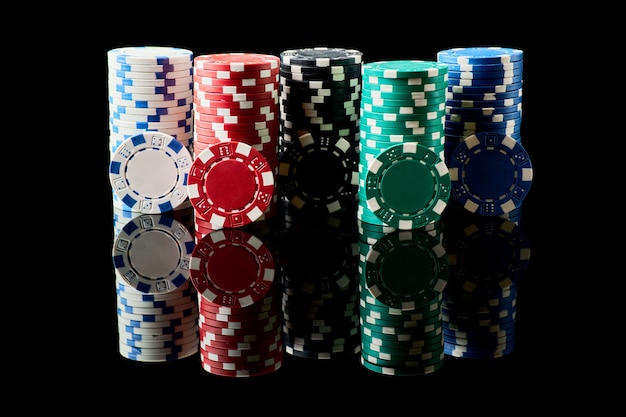 Pila di fiches del casinò isolate su sfondo nero riflettente