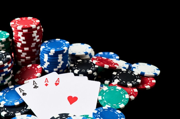 Pila di fiches e carte da gioco del casinò isolate su sfondo nero riflettente