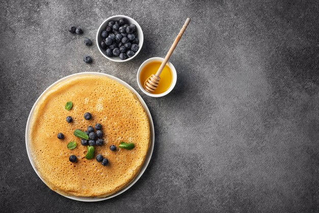 pila di frittelle su un piatto con miele e frutti di bosco, maslenitsa