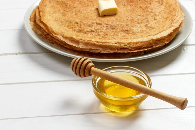 Pila di gustosi pancake con burro e miele per colazione