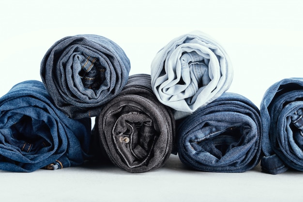 Pila di jeans rotolati differenti su bianco