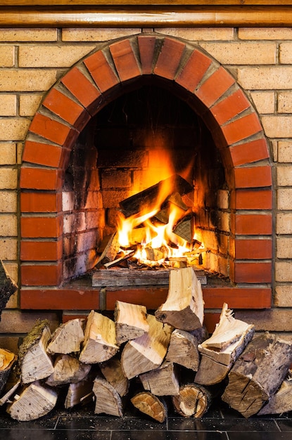 Pila di legno e fuoco nel camino interno del mattone