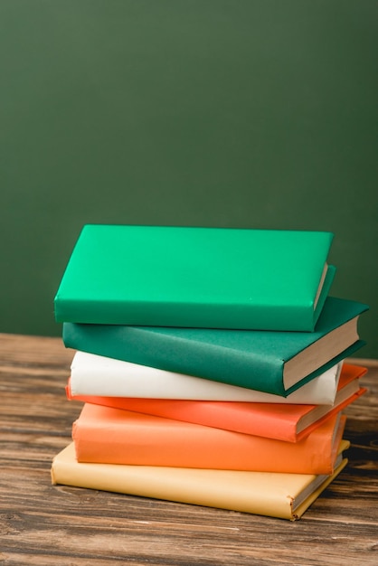 Pila di libri colorati su superficie di legno isolata su verde