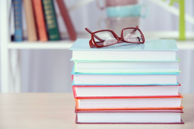 Pila di libri con gli occhiali sul tavolo di legno in camera