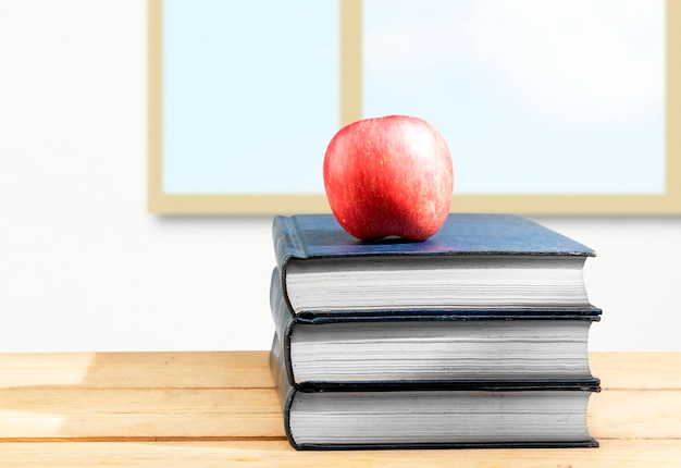 Pila di libri con mele sul tavolo di legno. Ritorno al concetto di scuola