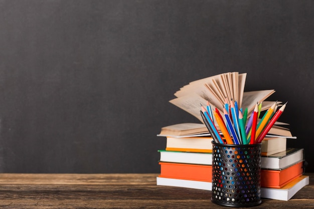 Pila di libri e cancelleria sullo sfondo del consiglio scolastico. Istruzione e ritorno al concetto di scuola.