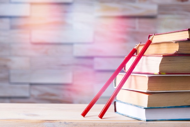 Pila di libri e due matite di legno rosse su legno, di nuovo a scuola