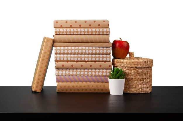 Pila di libri e mela sul ripiano del tavolo su sfondo bianco