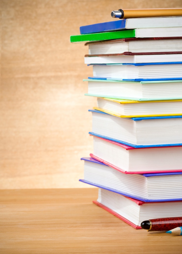 Foto pila di libri e penne sulla tavola di legno