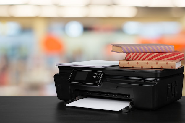 Pila di libri e stampante domestica su sfondo sfocato