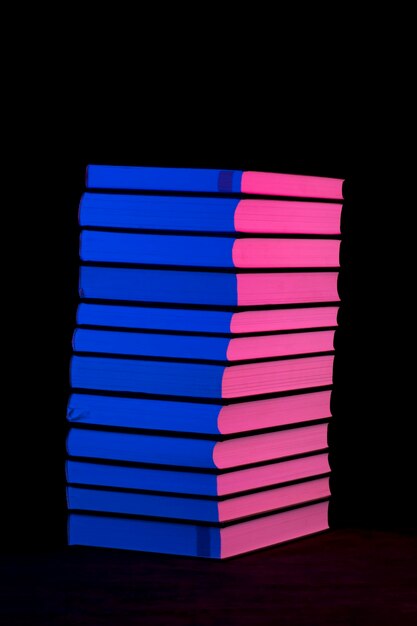 Pila di libri in luce rosa e blu su sfondo scuro