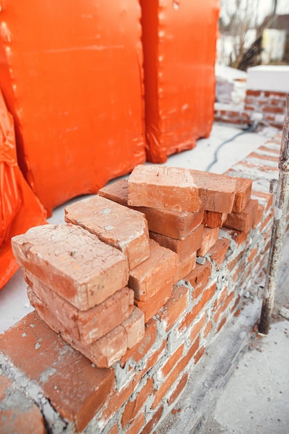 Pila di mattoni rossi sul processo di fondazione in calcestruzzo della costruzione di una casa Fondazione in calcestruzzo con mattoni per la posa Materiali da costruzione in cantiere