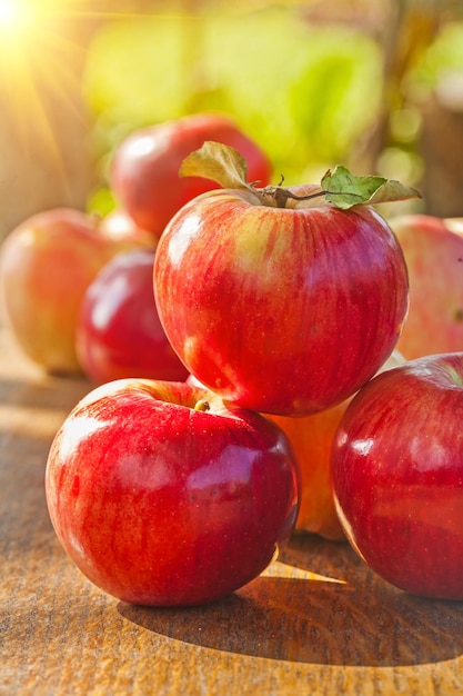 Pila di mele rosse mature fresche sulla tavola di legno in giardino