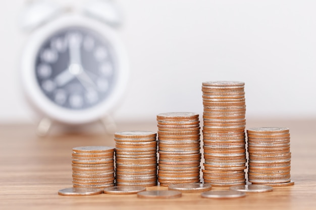Pila di monete con l&#39;orologio per il concetto di risparmio di denaro