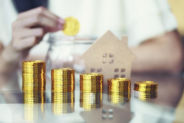 Pila di monete d&#39;oro con casa in legno