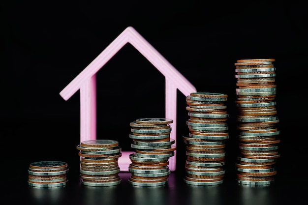 Pila di monete e modello di casa su sfondo bianco concetto di risparmio ipotecario
