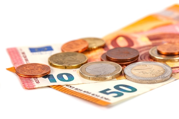 Pila di monete in euro e banconote su bianco, soldi