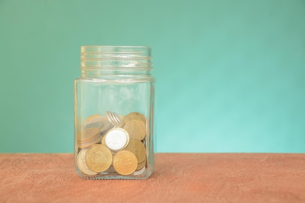 Pila di monete in un barattolo di vetro isolato su uno sfondo verdeconcetto di investimento per il risparmio di denaro
