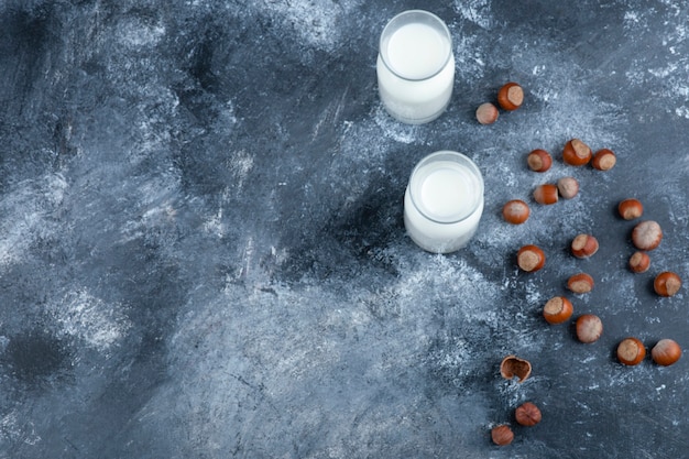 Pila di nocciole sgusciate biologiche con bicchieri di latte fresco.