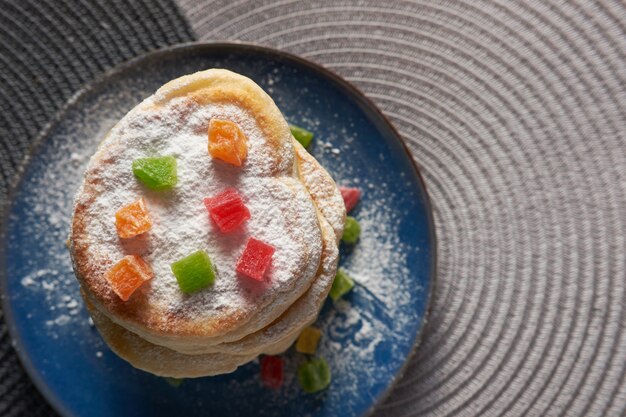 Pila di pancake in polvere con zucchero in polvere e decorato con frutta secca, vista da sopra