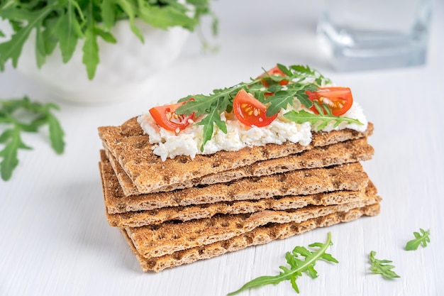 Pila di pane croccante tipo cracker contenente farina integrale con ricotta e pomodorini