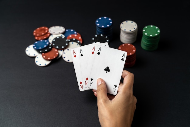 Pila di patatine e mano di donna con quattro assi sul tavolo. Concetto di gioco del poker