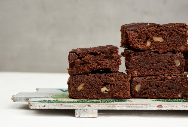 Pila di pezzi al forno quadrati di brownie torta al cioccolato con noci