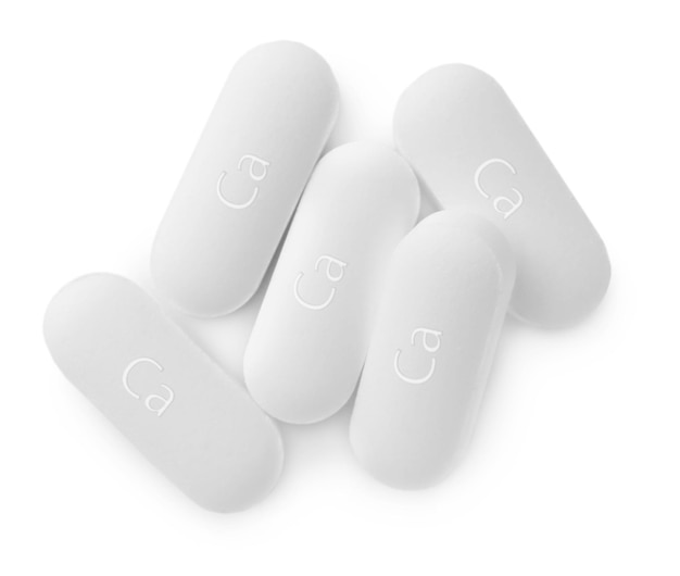 Pila di pillole di supplemento di calcio su fondo bianco piatto