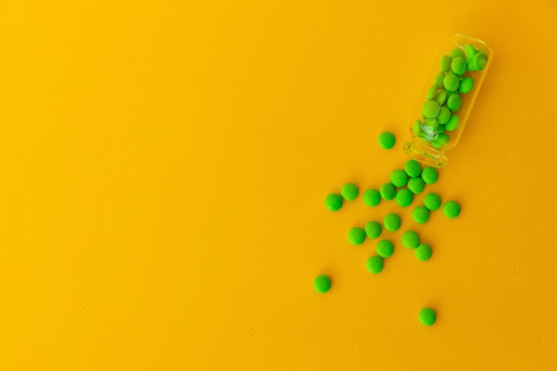 Pila di pillole verdi su sfondo giallo.Vista dall'alto, flatlay. Mucchio di compresse, pillole di vitamine. Integratore alimentare di Spirulina, medicina alternativa