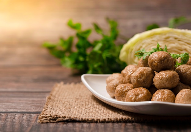 Pila di polpette al forno in piatto bianco su di legno