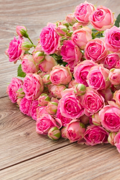 Pila di rose fresche rosa sulla tavola di legno