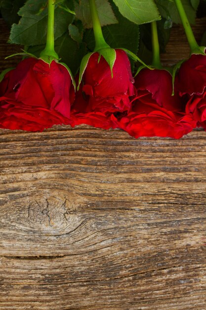 Pila di rose rosse vivd sulla tavola di legno con lo spazio della copia