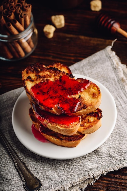 Pila di toast alla francese con sciroppo di frutti di bosco su piastra bianca