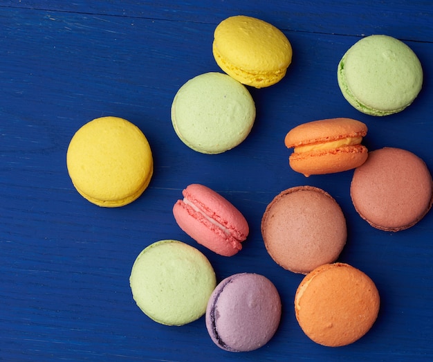 Pila di torte di macarons al forno rotonde multicolori su un fondo di legno blu, fine su