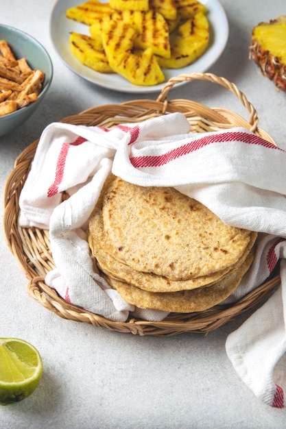 Pila di tortillas di mais messicane in un vassoio di vimini coperto con un asciugamano da cucina
