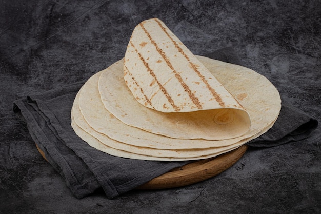 Pila di tortillas di mais su sfondo scuro. Cibo messicano.