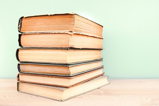 Pila di vecchi libri usati su tavola di legno e sfondo blu Pila di vecchi libri con copertina rigida vintage