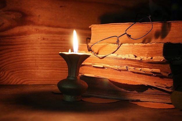 Pila di vecchio libro a brandelli su un tavolo di legno candela e bicchieri accesi