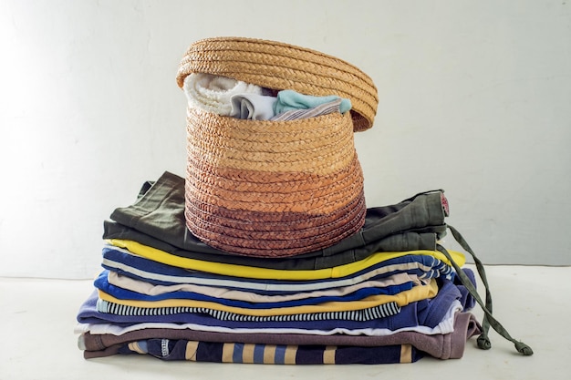 Pila di vestiti usati e un cesto della biancheria Organizzazione del guardaroba Concetto di vita sostenibile smistamento di seconda mano per il riciclaggio