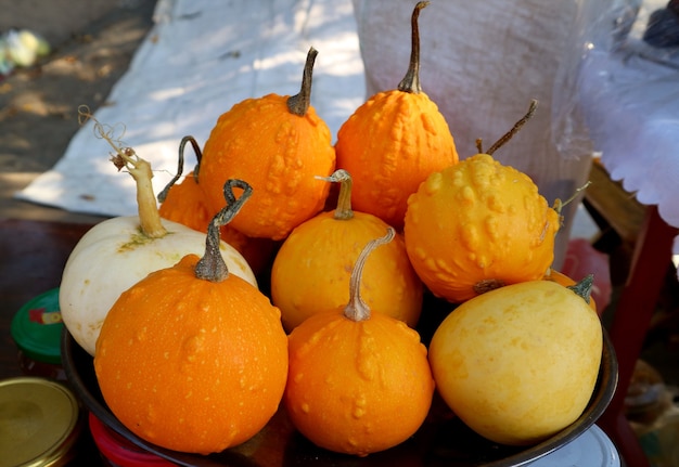 Pila di vivaci zucche di colore giallo e arancione che vendono al mercato