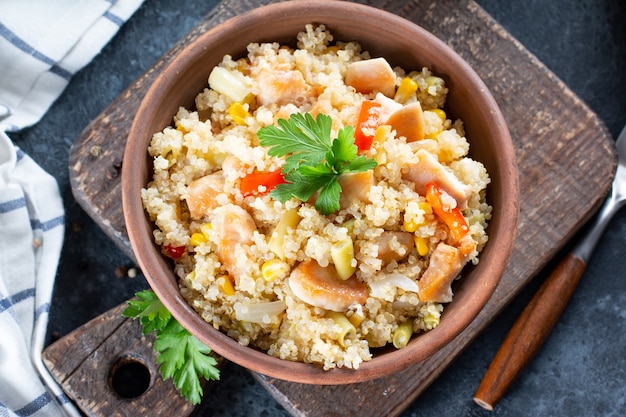 Pilaf di quinoa con pollo e verdure su tavola di legno, messa a fuoco selettiva